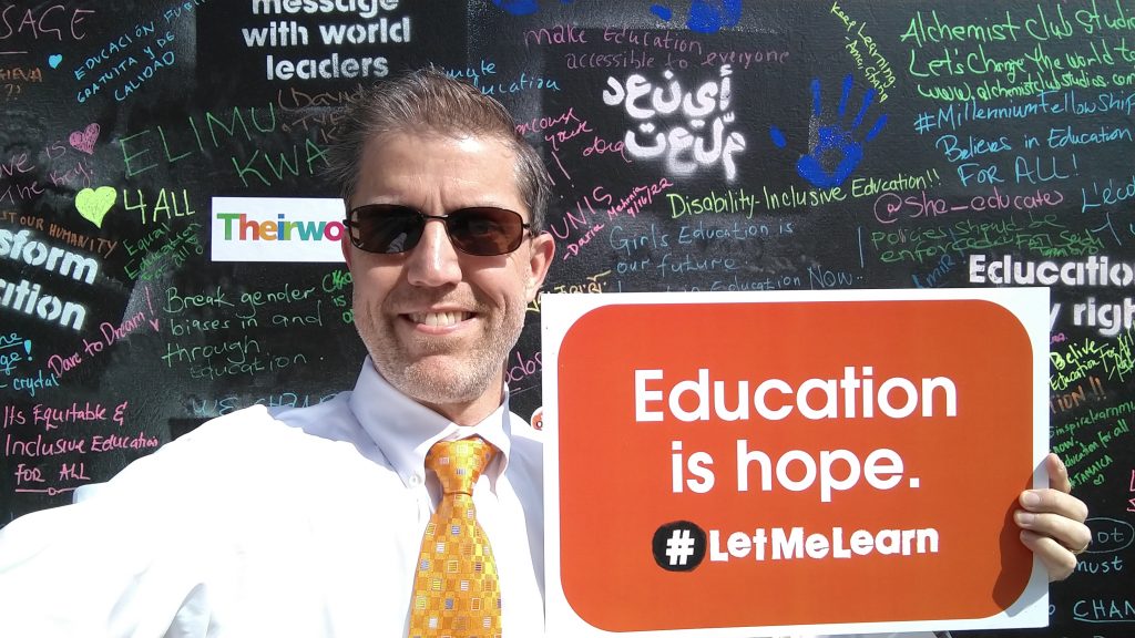 A photo of Dr. Cable Green holding a red sign that says